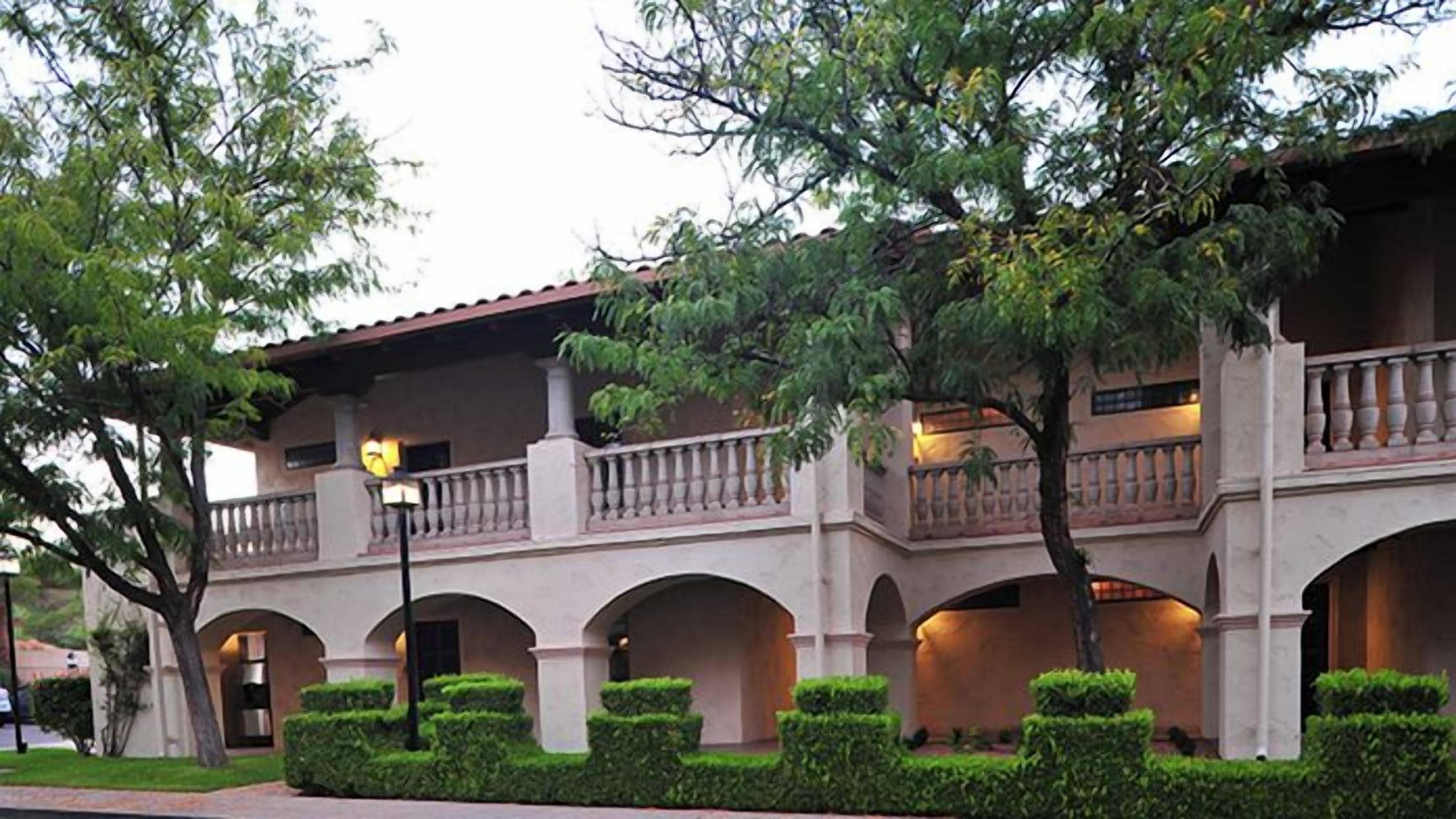 A building with a covered patio area, multiple arches, and a balcony with railings.