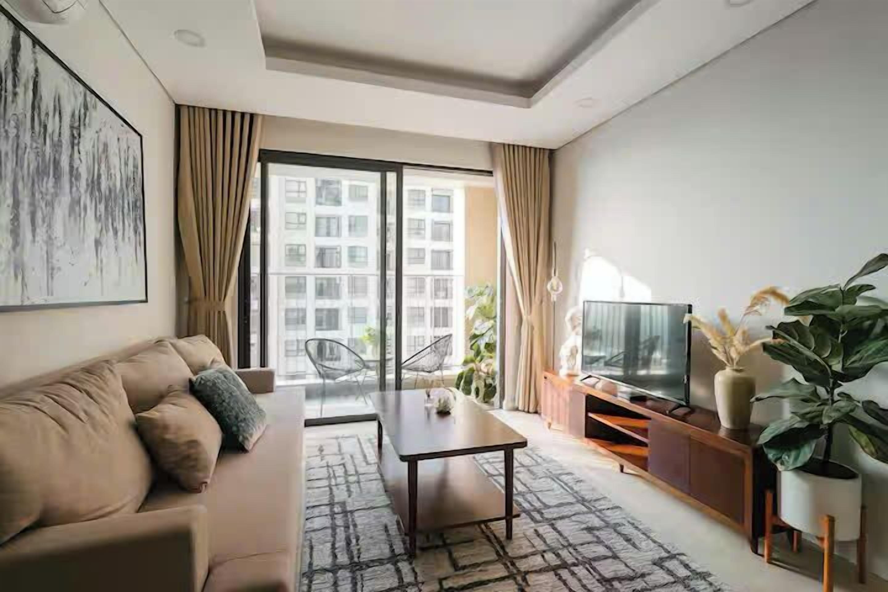 A modern living room with a sofa, a coffee table, a TV, and a large window with curtains.