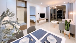 Een moderne hotelkamer met een zithoek, een televisie, een balkon met uitzicht over de stad en een grote potplant.
