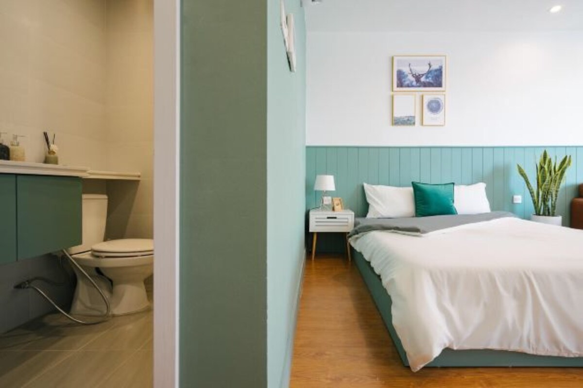 A bedroom with a bed, a nightstand, a bedside table, a lamp, and a wall-mounted picture.