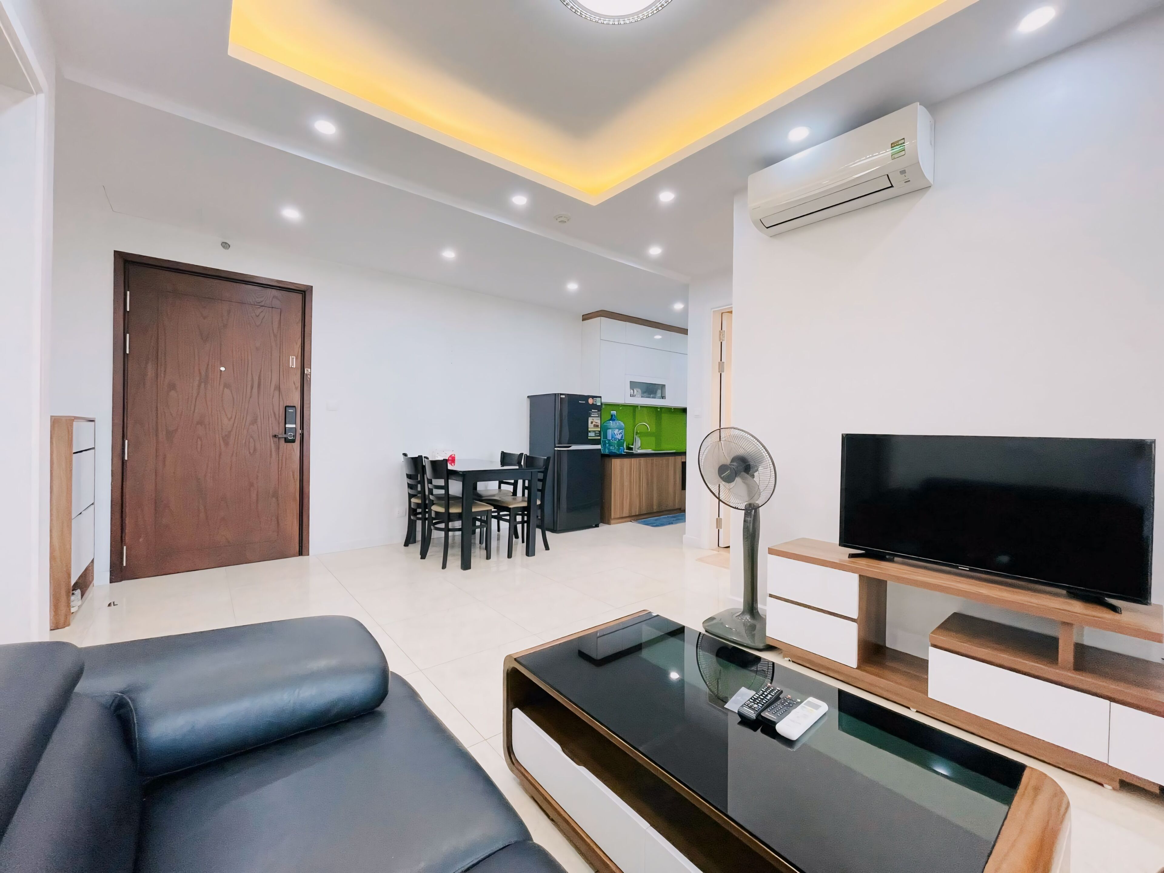 A modern living room with a sofa, TV, and a dining area with chairs and a table.