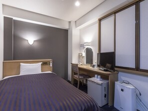 A hotel room with a bed, desk, chair, and a small refrigerator. - Hotel HORAIRE Saijo (Saijo)