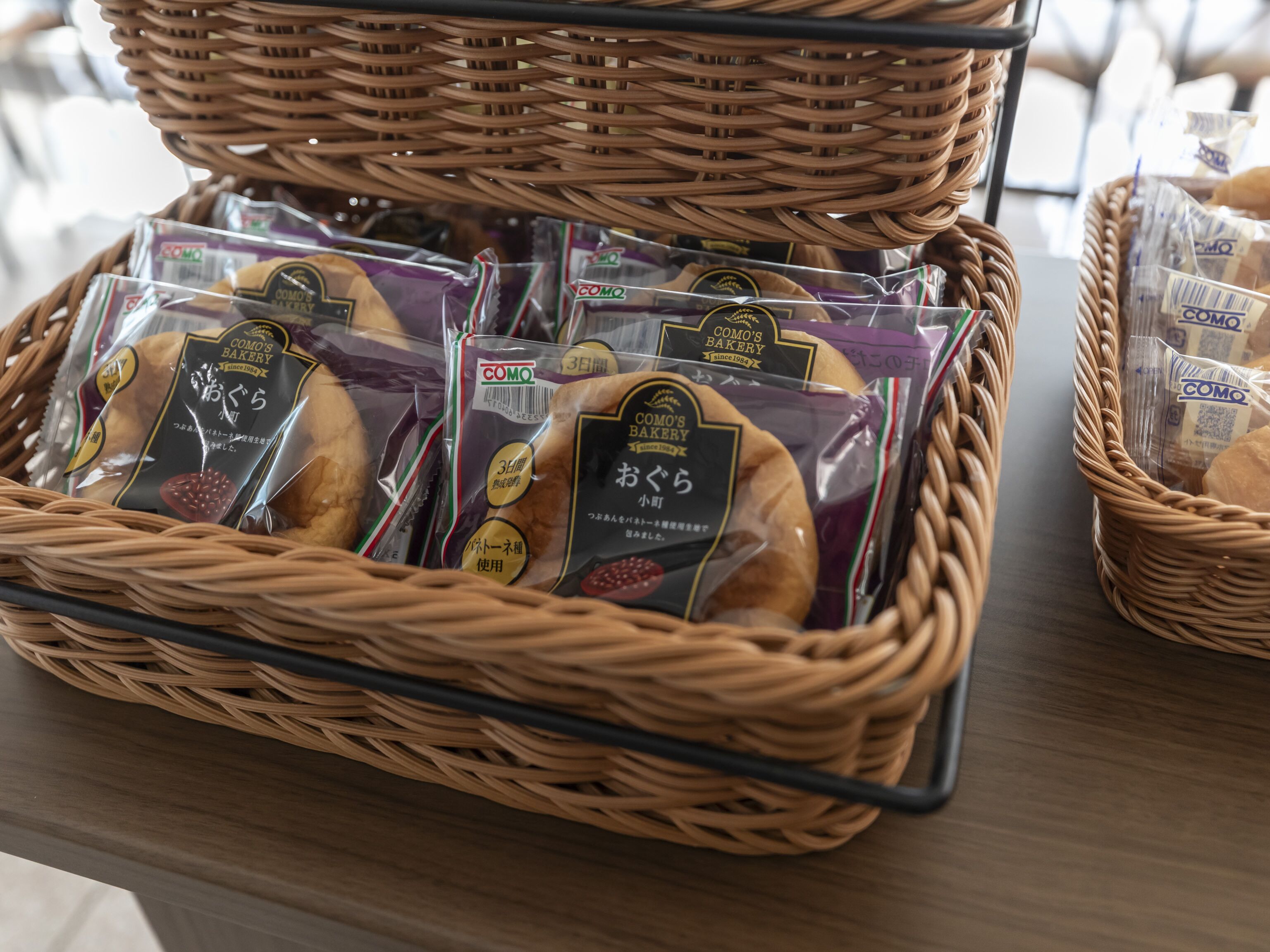 Een rieten mand gevuld met verpakt brood en een rieten mand op een tafel.