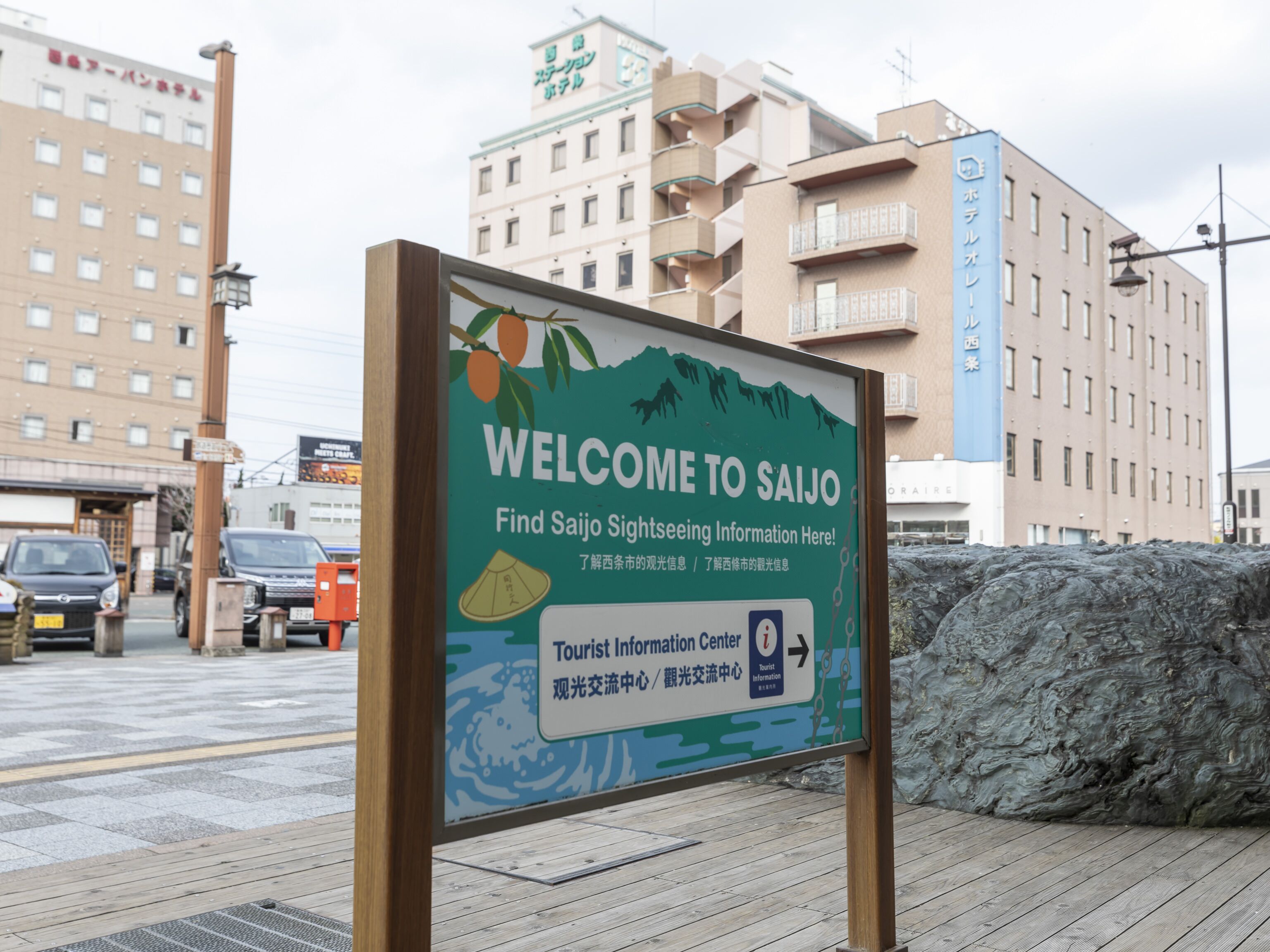 A welcome sign for Saijo with a tourist information center direction.