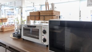 A kitchen counter with a microwave, a toaster, and a basket of bread. - Hotel HORAIRE Saijo (Saijo)