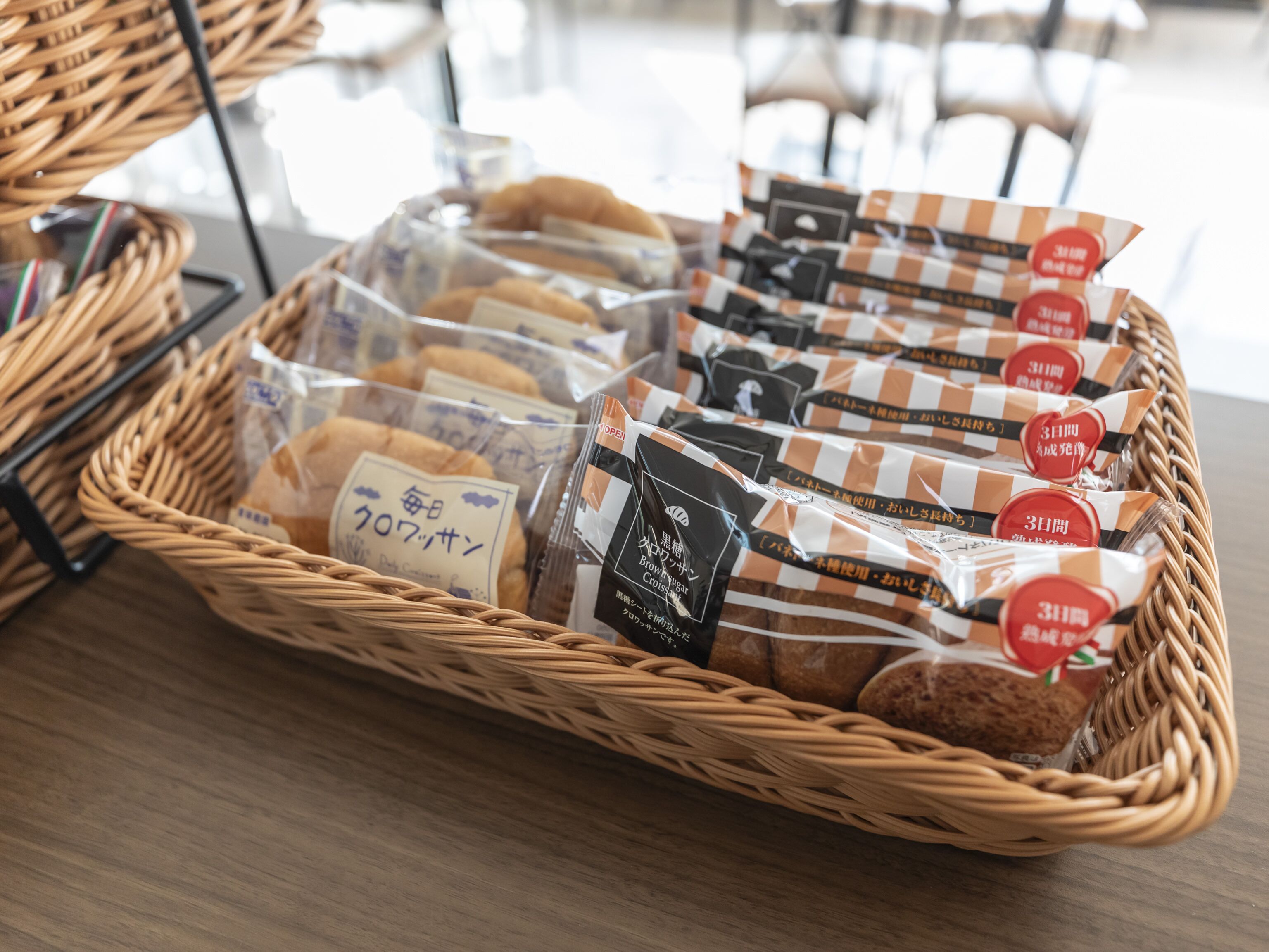 A wicker basket filled with packaged food items on a wooden table.