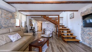 Ein geräumiger Wohnbereich mit einer Holztreppe, Steinwänden und einem Sofa.