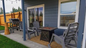 Une terrasse extérieure avec un barbecue, une table et des chaises.
