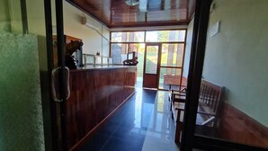 Un'area reception con una scrivania in legno, una panca e una porta in vetro che dà sull'esterno.