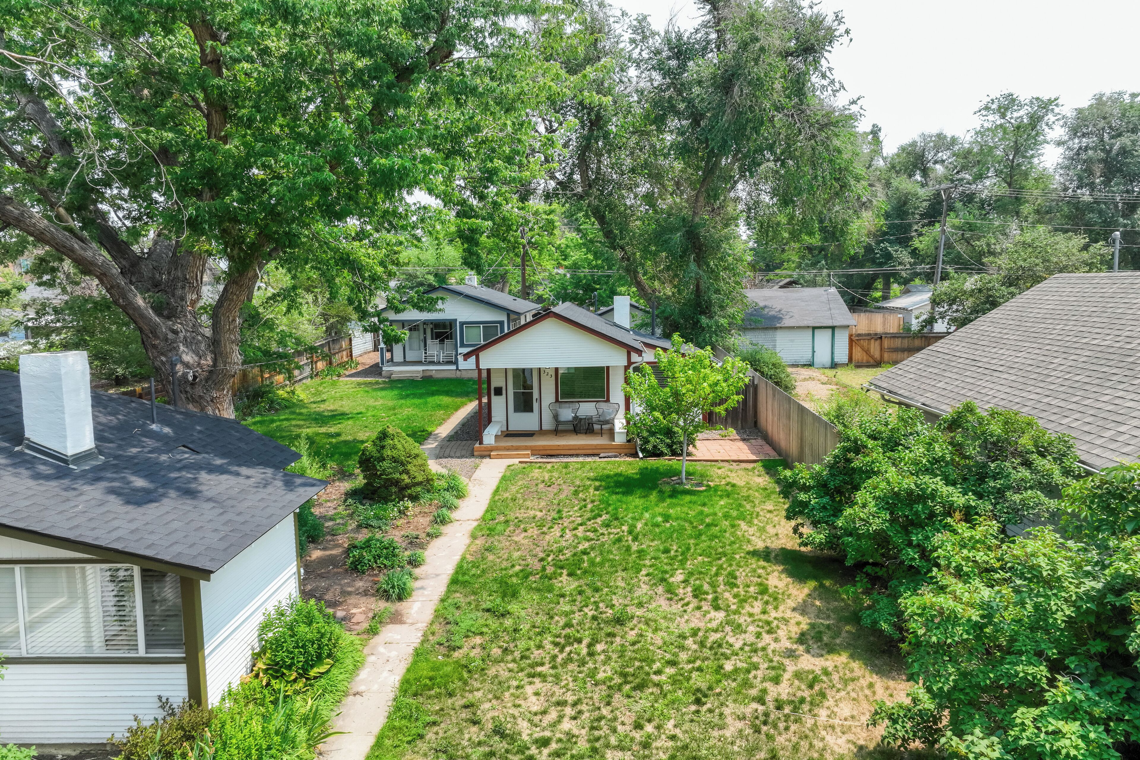 A residential area with a small house featuring a front porch, a visible garage, and a well-maintained lawn.