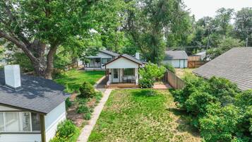 A residential area with a small house featuring a front porch, a visible garage, and a well-maintained lawn.