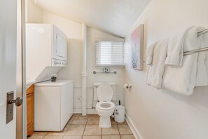 A compact bathroom with a toilet, a small washing machine, and a towel rack. - Sophies Cottage (Colorado Springs)