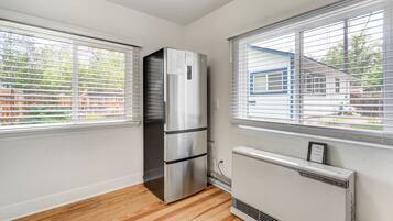A kitchen with a stainless steel refrigerator, a built-in oven, and a white wall-mounted air conditioner.