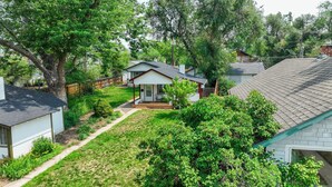 A residential house with a front yard, a wooden deck, and a large tree. - Sophies Cottage (Colorado Springs)