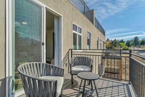 A balcony with two chairs and a table, a sliding glass door, and a view of the surrounding area. - Elevated View (Colorado Springs)