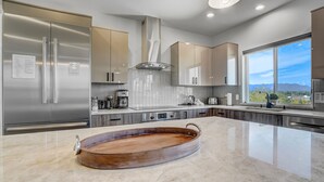 A modern kitchen with stainless steel appliances, a large island, and a view of the mountains. - Elevated View (Colorado Springs)