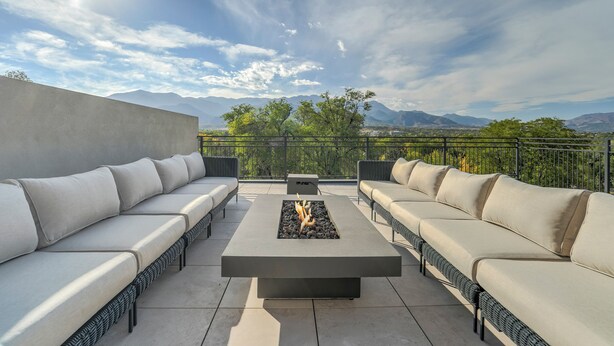 A rooftop terrace with a fire feature, two sofas, and a view of mountains. - Elevated View (Colorado Springs)