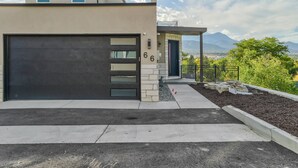 A modern two-story house with a garage, a covered porch, and a view of mountains. - Elevated View (Colorado Springs)