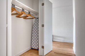 Features a closet with a patterned shower curtain and a door with a silver handle.