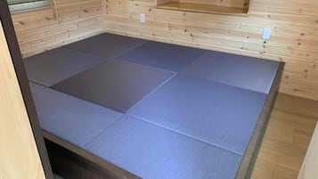 A room with a wooden floor and a large, dark-colored mat covering the floor.