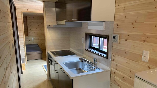 A compact kitchen with a built-in stove, a sink, and a window above the sink. - Kita-alps BASE Onsenkyo Camp (Omachi)