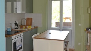 Ett kompakt kök med en bänkskiva i trä, vita skåp och en inbyggd ugn.