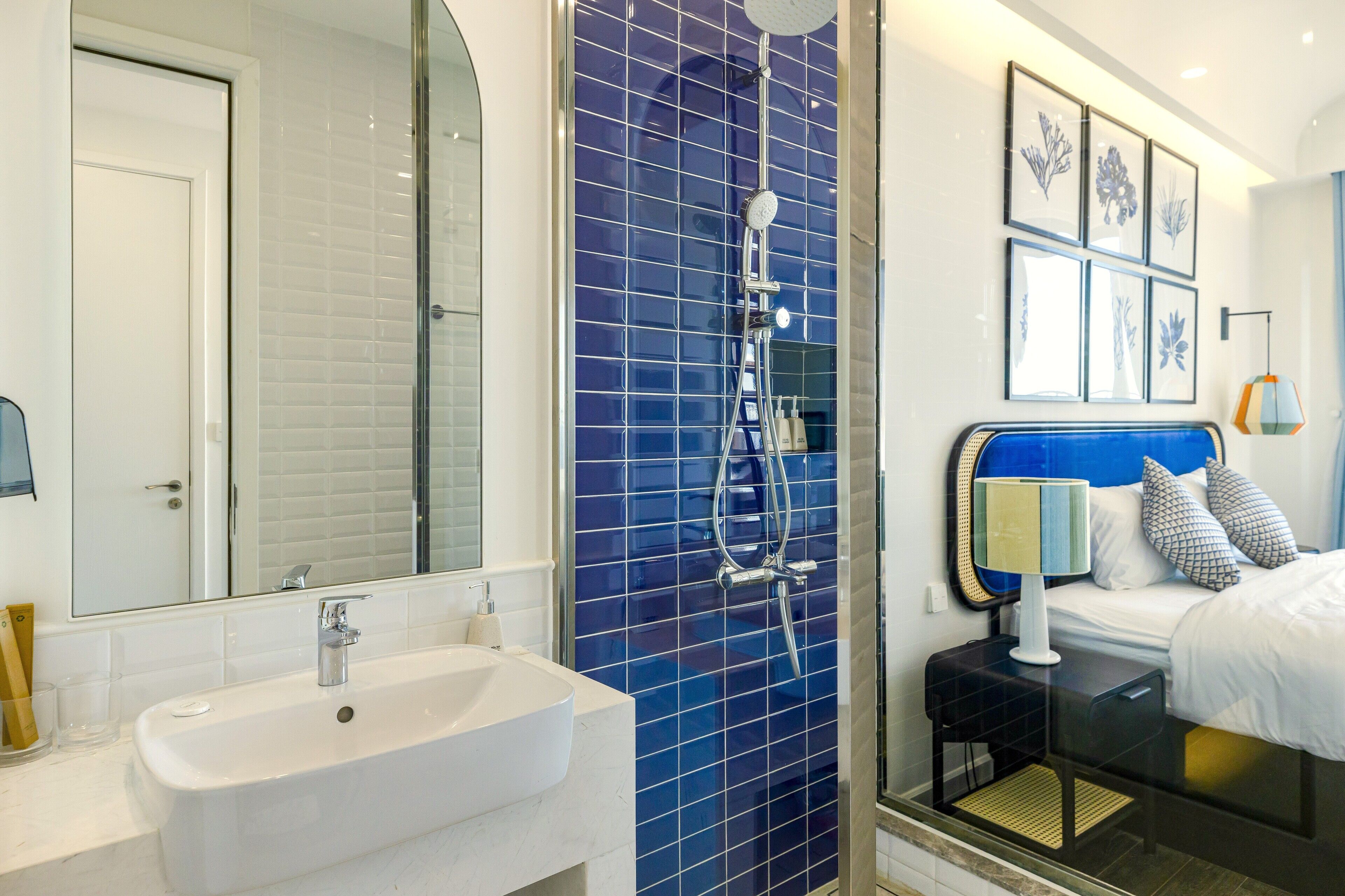 Une salle de bain moderne avec un lavabo blanc, une douche aux carreaux bleus et un lit avec une tête de lit bleue.