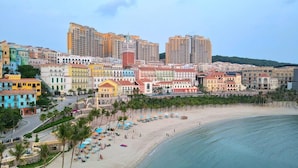 Un paysage urbain situé sur la côte, avec des bâtiments aux couleurs vives, une plage et une promenade.