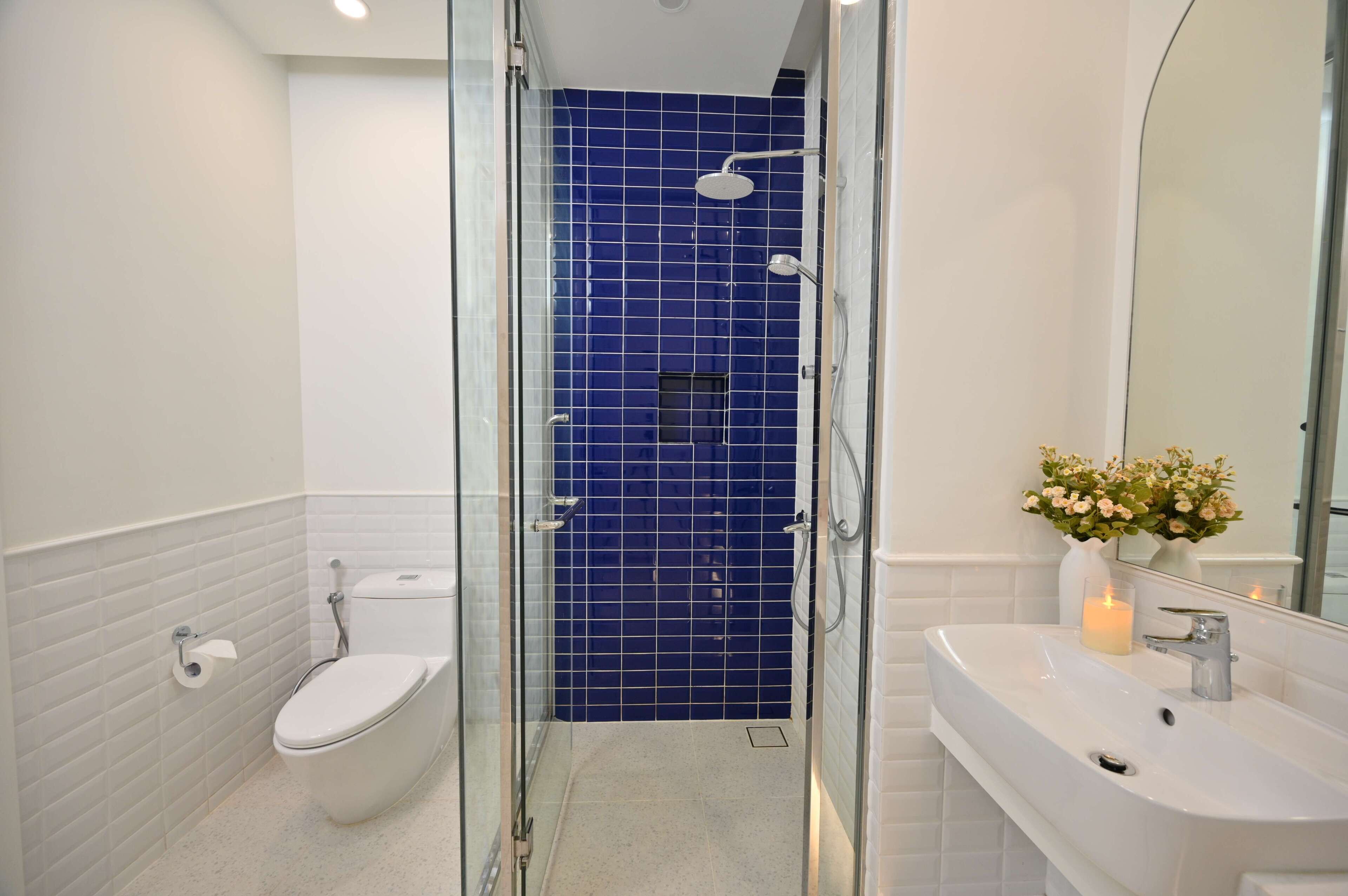 Un bagno con doccia vetrata, WC bianco e lavabo con un vaso di fiori.