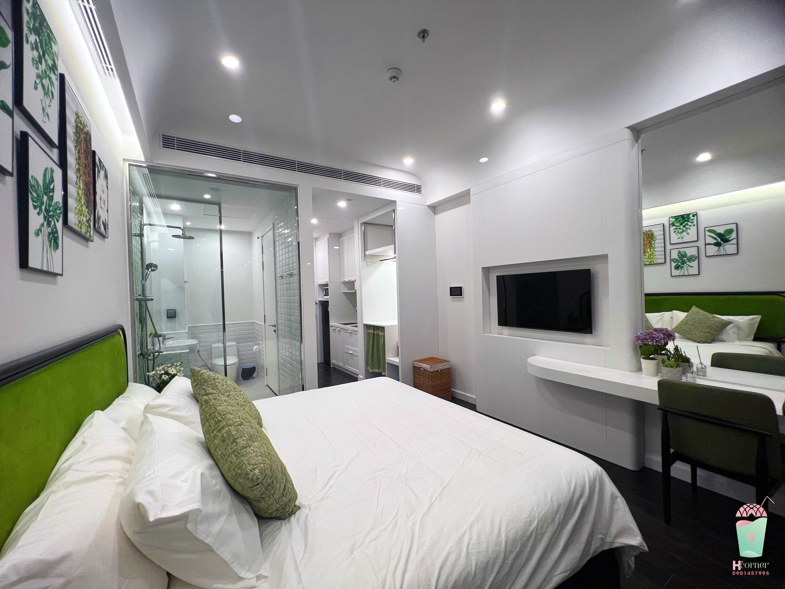 A modern hotel room with a bed, a desk, a TV, and a shower area.