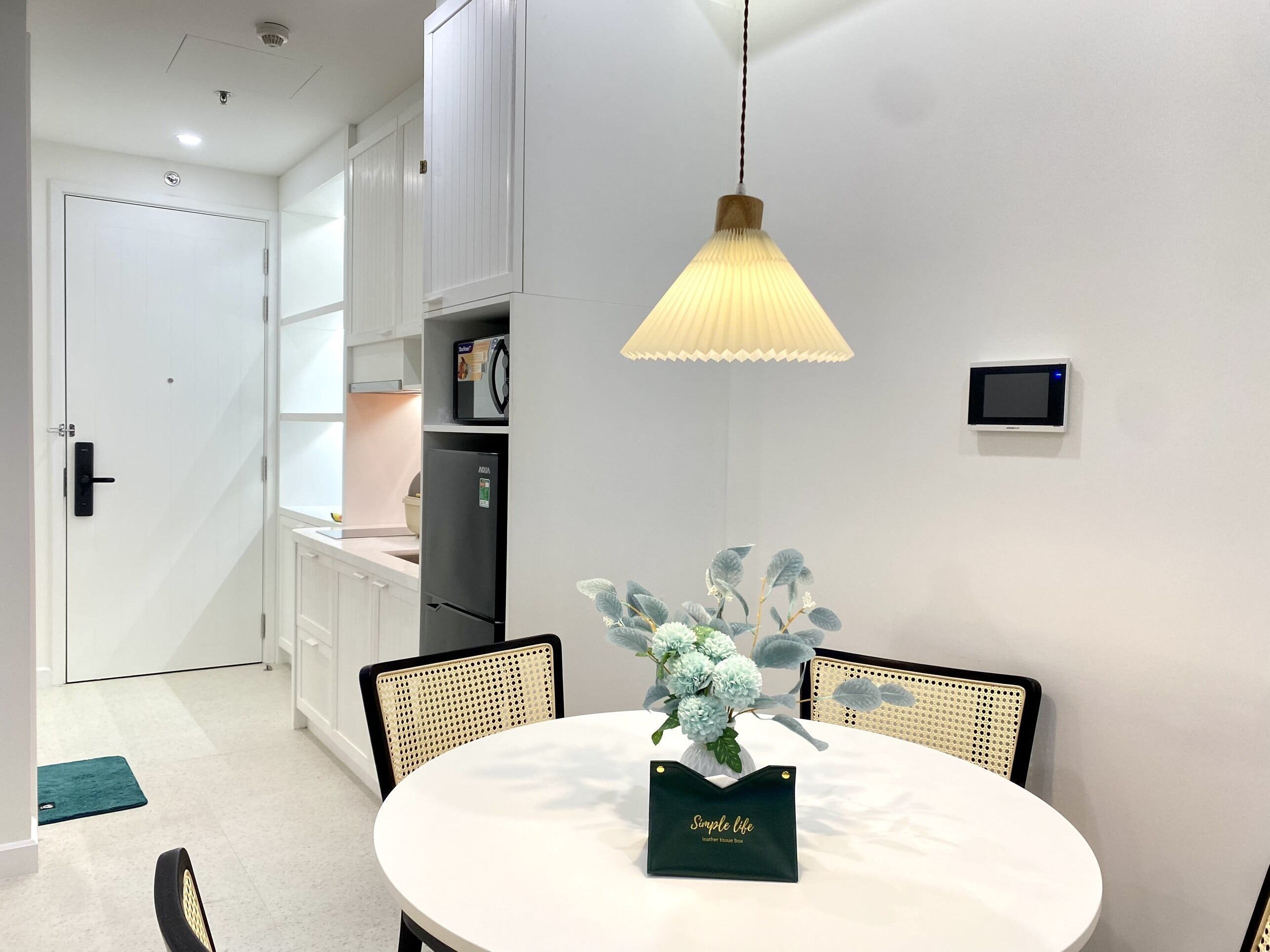 Una cucina moderna con mobili bianchi, un frigorifero nero e una lampada a sospensione.