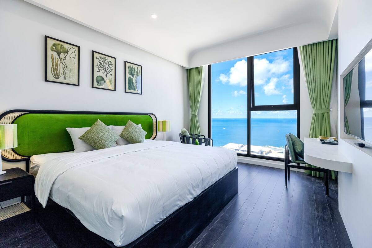 Een moderne hotelkamer met een groot bed, een bureau en uitzicht op zee.