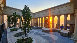 Un vaste espace extérieur doté d’une piscine, de coins salon et offrant une vue sur le coucher de soleil.