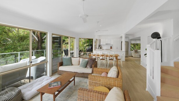 A spacious living area with a large window, a dining area, and a kitchen. - Villa Luna (Avoca Beach)
