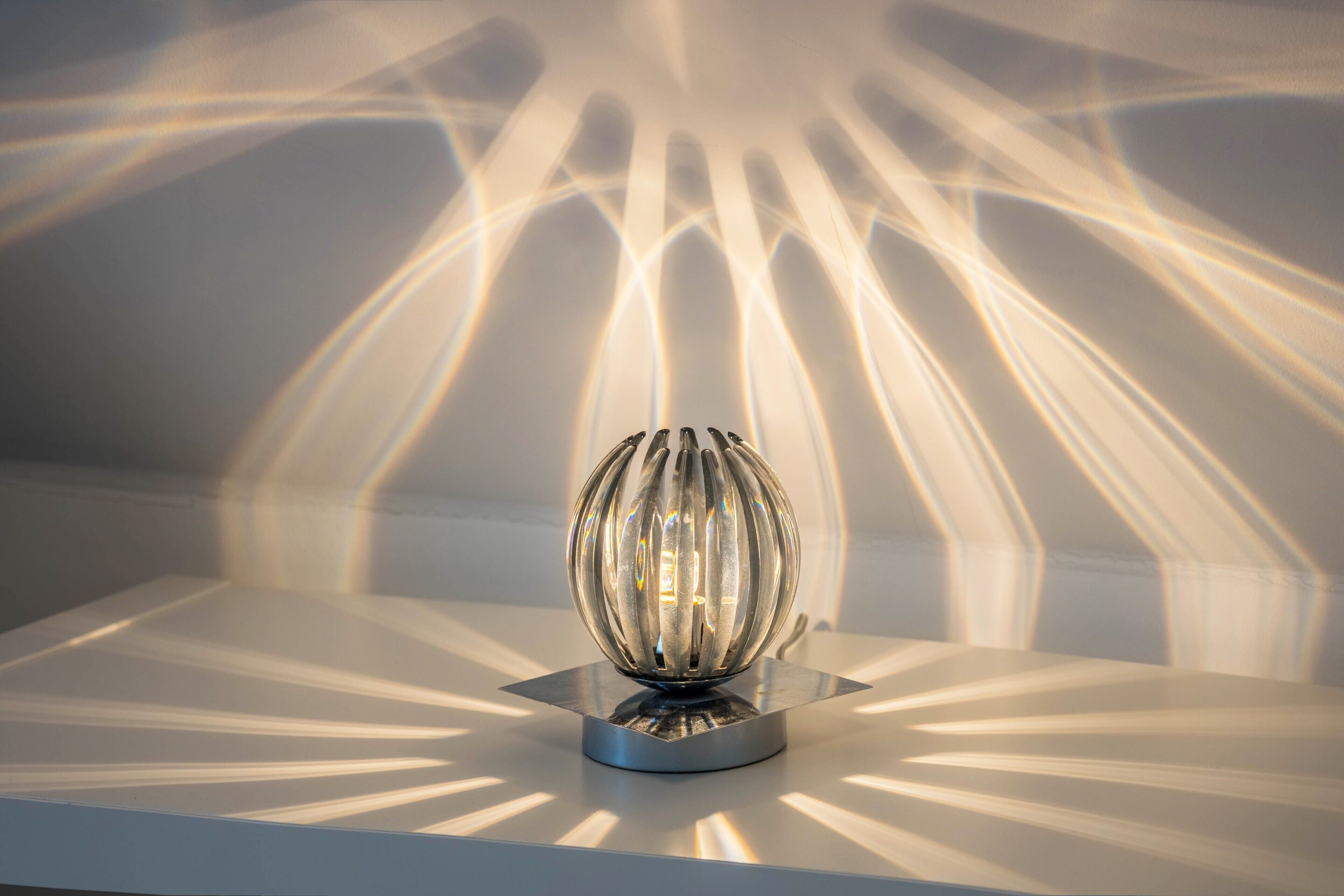 A spherical light fixture on a metallic base with a reflective surface.