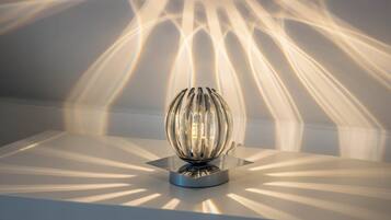 A spherical light fixture on a metallic base with a reflective surface.