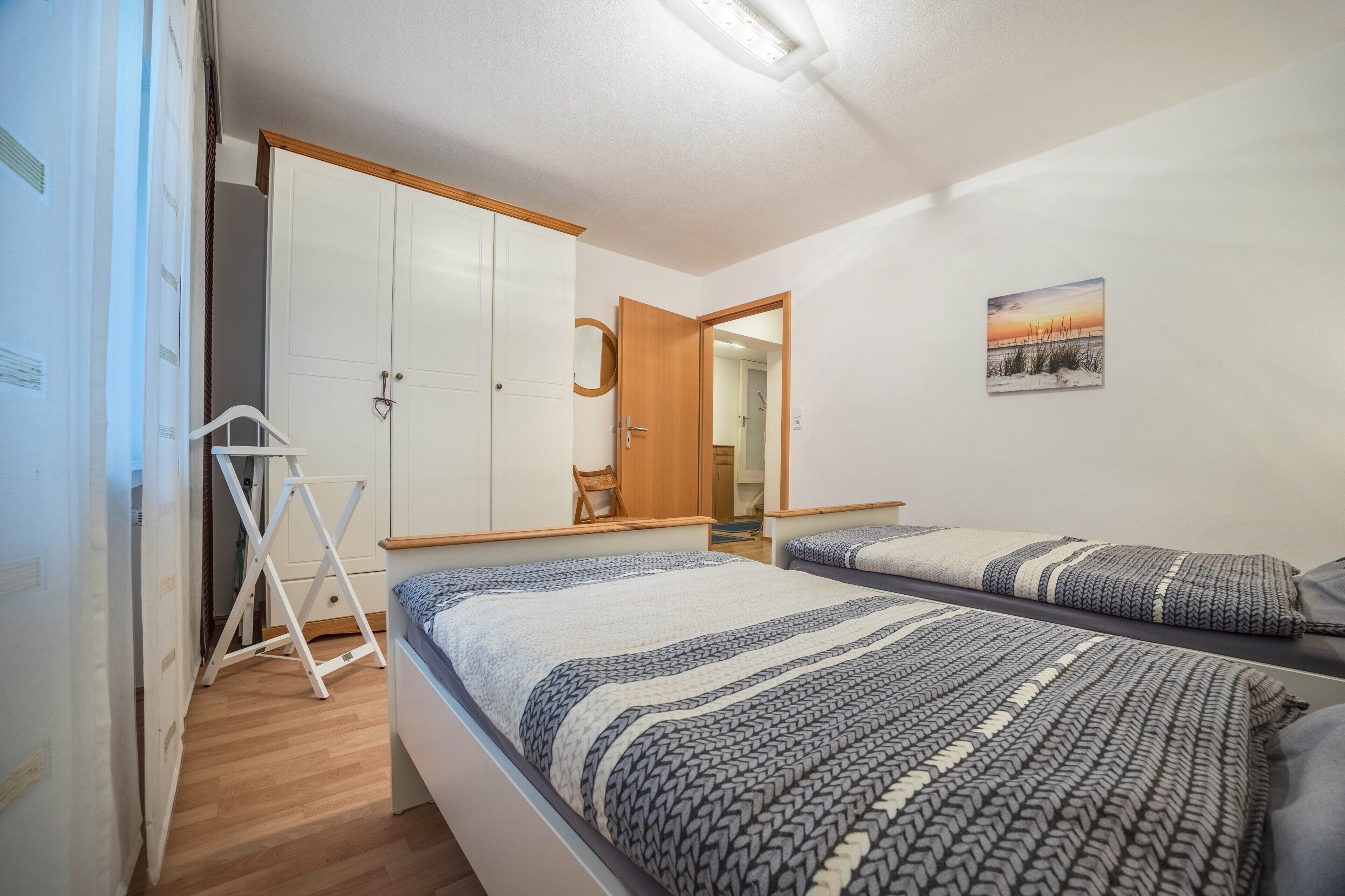 Ein Schlafzimmer mit zwei Betten, einem Kleiderschrank, einem Spiegel und einem Bild an der Wand.