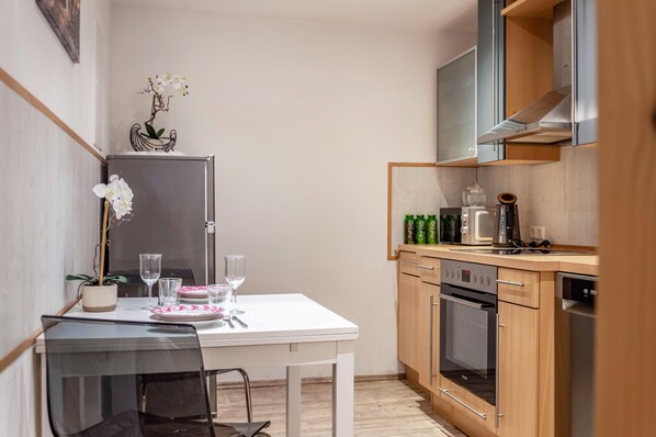 Une cuisine compacte comprenant une table à manger, des chaises, un réfrigérateur, un four, un lave-vaisselle et un four à micro-ondes.