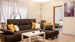 Ein modernes Wohnzimmer mit einer Couch, einem Couchtisch und einem Bett im Hintergrund.