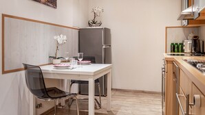 Eine kleine Küche mit Kühlschrank, einem Esstisch mit Stühlen und einer Kücheninsel mit Spüle.