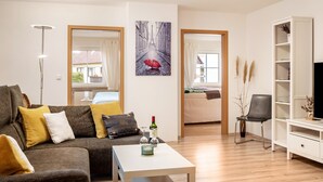Ein modernes Wohnzimmer mit einer Couch, einem Couchtisch und einem Gemälde einer Straßenszene.