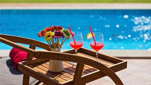 A wooden chair with a tray holding a vase of colorful flowers and two glasses of red drink with straws.