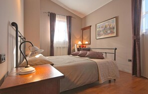 Une chambre à coucher avec un lit, une table de chevet, une lampe et un tableau au mur.