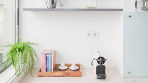 Una cocina moderna con encimeras blancas, electrodomésticos de acero inoxidable y un ventanal con una planta.