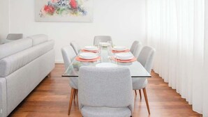 Un comedor con una mesa preparada para cuatro, un sofá y un cuadro en la pared.
