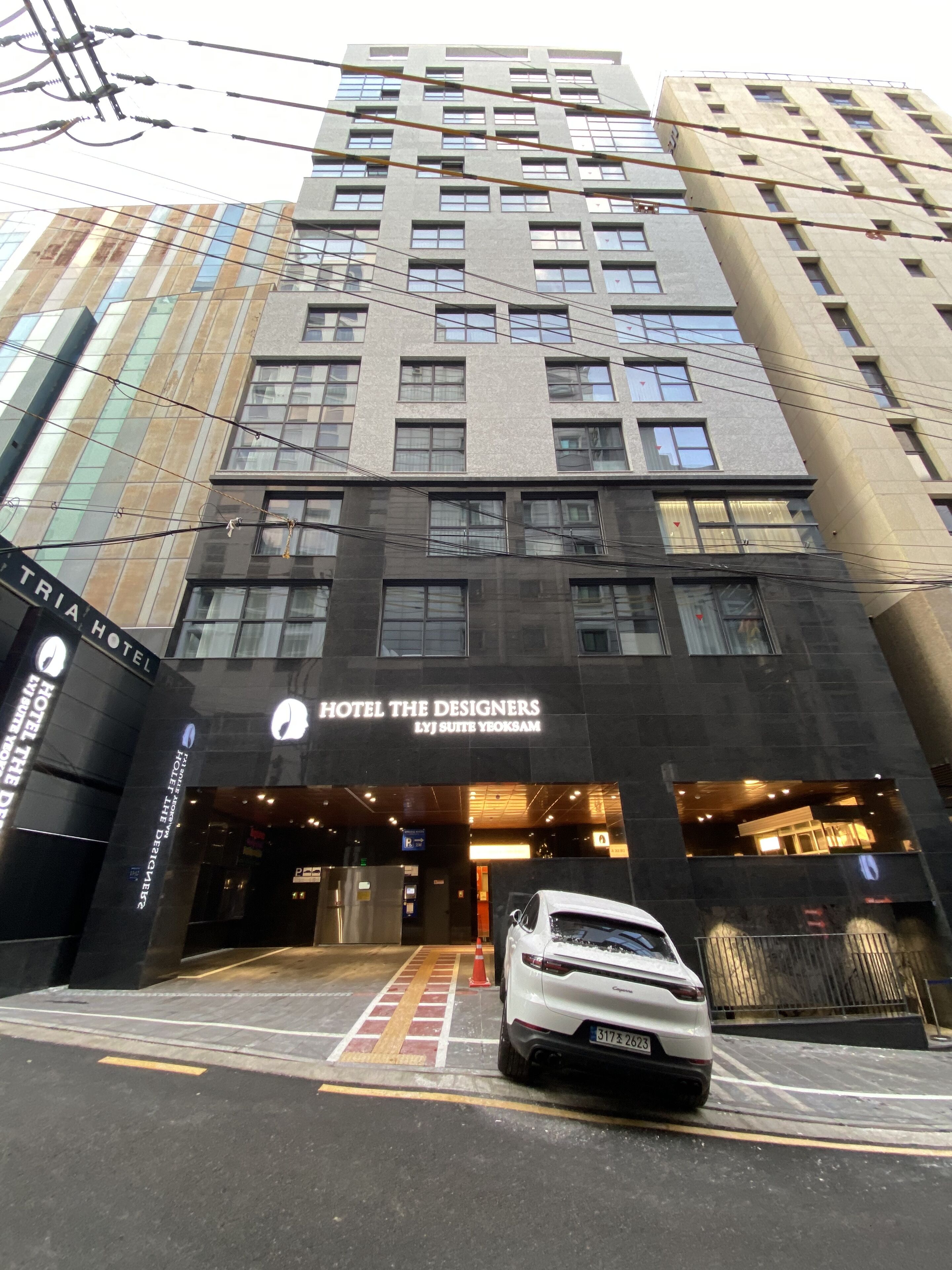 A modern hotel entrance with a white car parked in front.