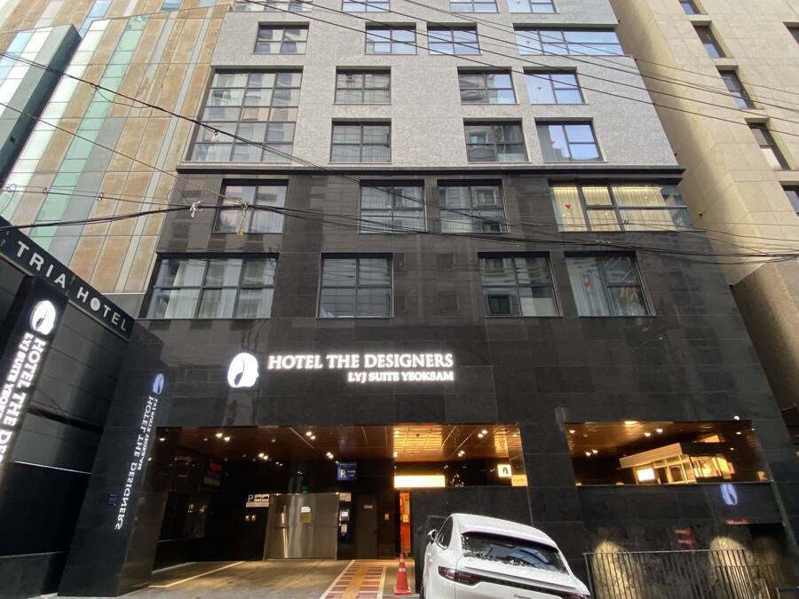 A modern hotel entrance with a white car parked in front.