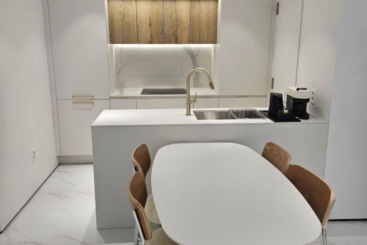 A modern kitchen with a white countertop, a built-in sink, and a window above the sink.