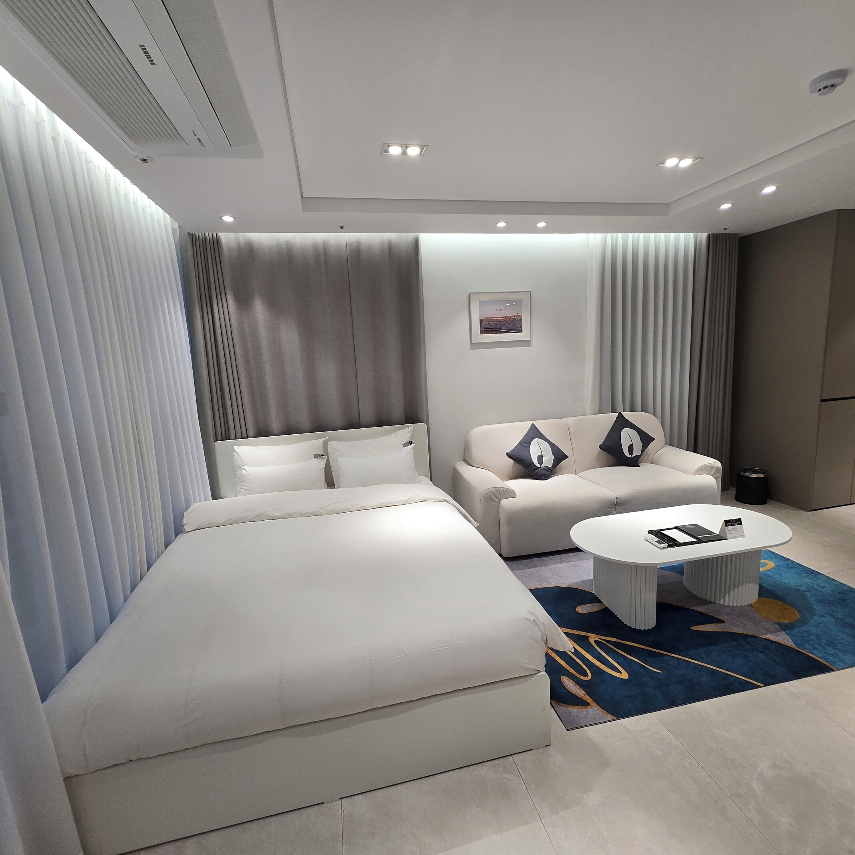 A modern hotel room with a large bed, a sofa, and a coffee table.