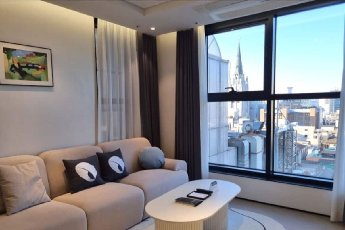 Een moderne woonkamer met een bank, een salontafel en een groot raam met uitzicht op de stad.